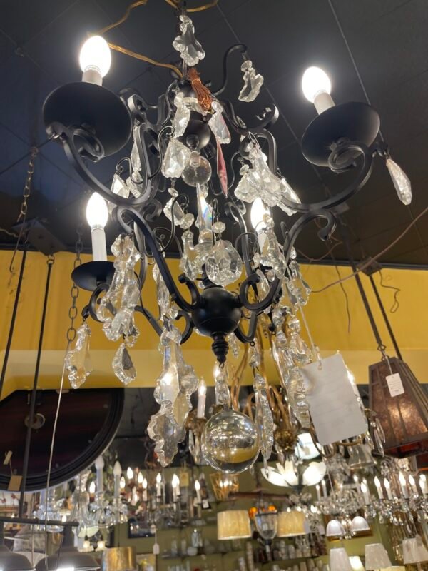 Bottom view of chandelier showing hanging glass orb and iron arms