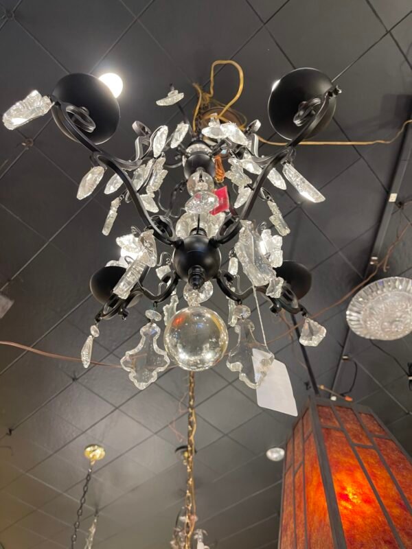 Ornate scrollwork on chandelier frame with lighted bulbs
